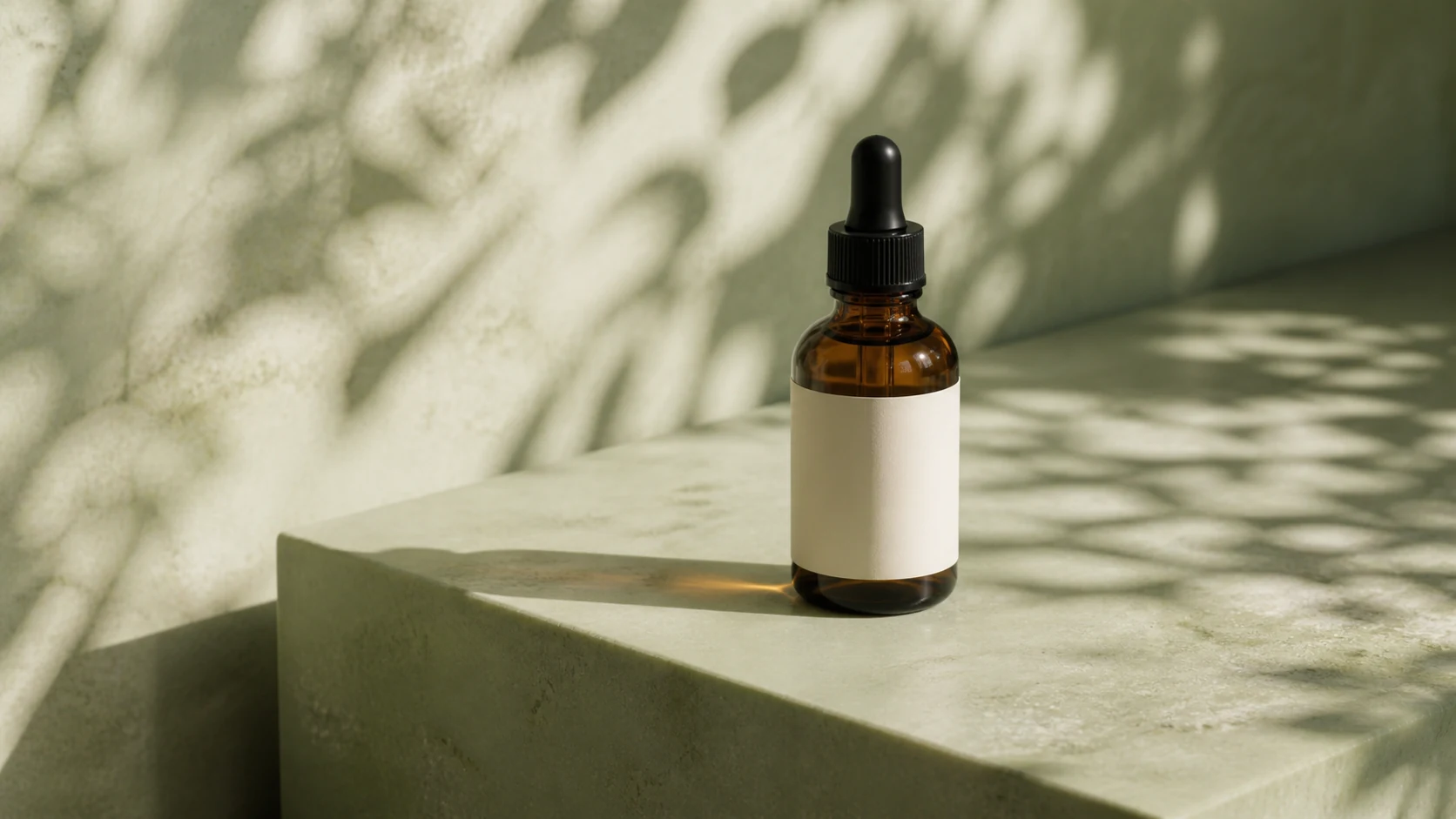 Blank-label amber serum bottle on a pale sage stone pedestal